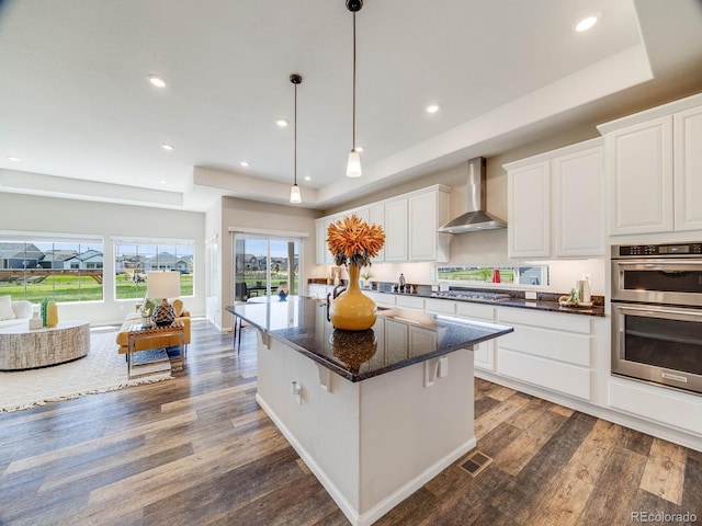 16448 E 111th Pl, Commerce City, CO 80022 - kitchen with wall chimney range hood, appliances with stainless steel finishes, wood finished floors, white cabinets, and recessed lighting