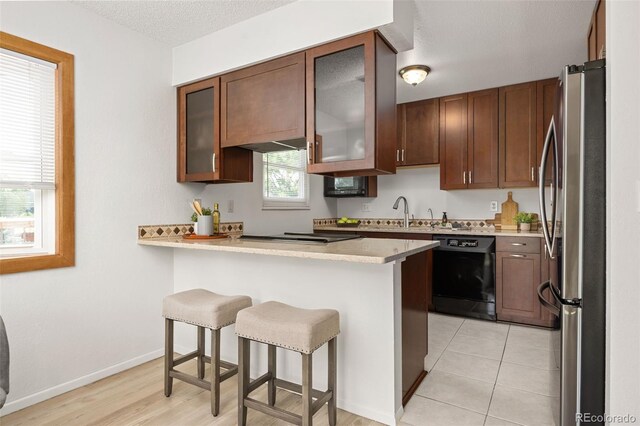 1245 Ceres Dr, Lafayette, CO 80026 - kitchen featuring black dishwasher, freestanding refrigerator, a peninsula, a kitchen bar, and light countertops