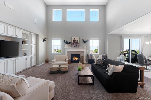 living area featuring baseboards, carpet, a chandelier, and a tiled fireplace