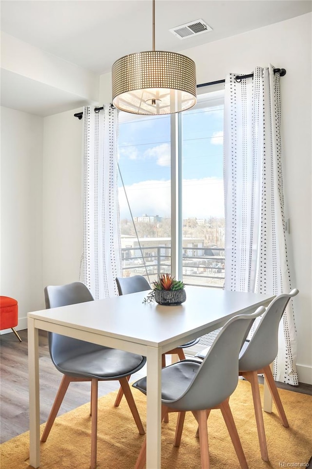 dining space featuring visible vents, baseboards, and wood finished floors