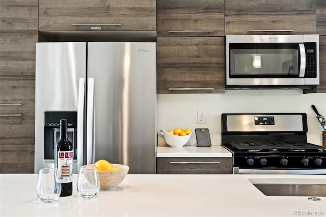 kitchen featuring light countertops, appliances with stainless steel finishes, and dark brown cabinetry