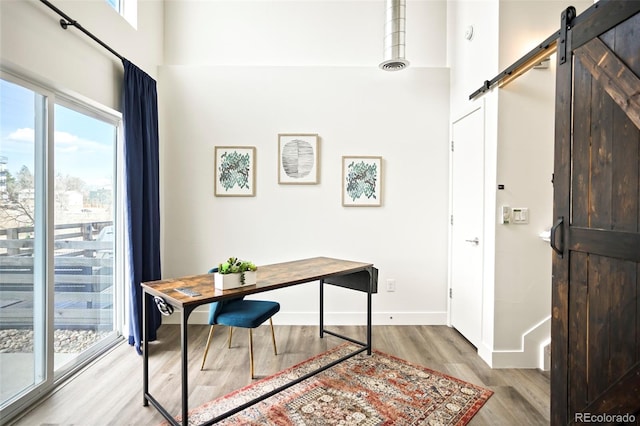 home office featuring a barn door, baseboards, a wealth of natural light, and wood finished floors