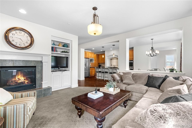 16207 Cadland Ct, Parker, CO 80134 - living area with built in shelves, a chandelier, a fireplace, and dark colored carpet