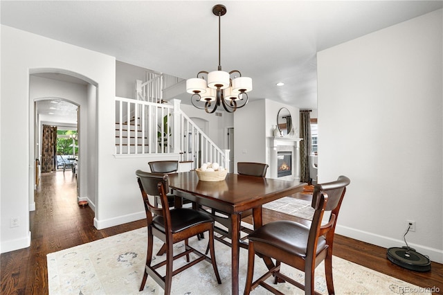 16207 Cadland Ct, Parker, CO 80134 - dining area with stairway, wood finished floors, a chandelier, arched walkways, and a glass covered fireplace