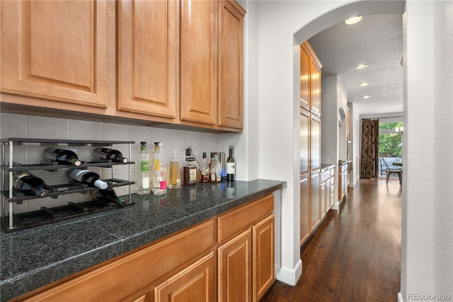 16207 Cadland Ct, Parker, CO 80134 - indoor dry bar featuring arched walkways, decorative backsplash, dark wood-style flooring, and recessed lighting