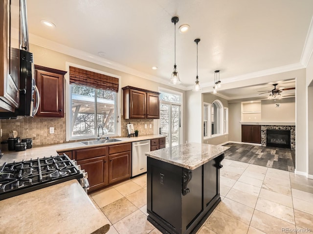 kitchen with a sink, stainless steel dishwasher, open floor plan, a fireplace, and crown molding