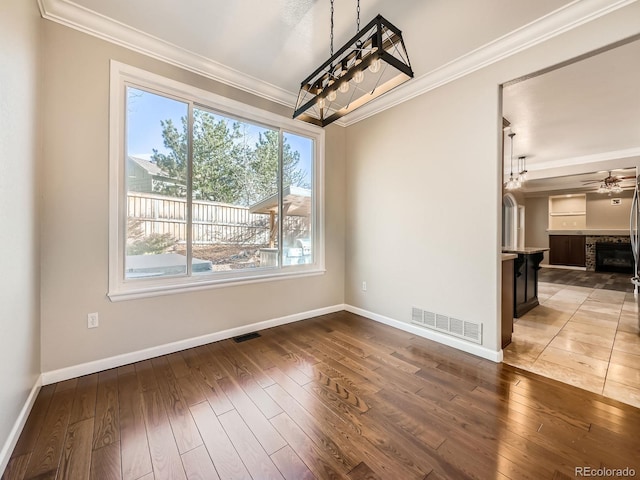 unfurnished dining area with visible vents, ornamental molding, and hardwood / wood-style flooring