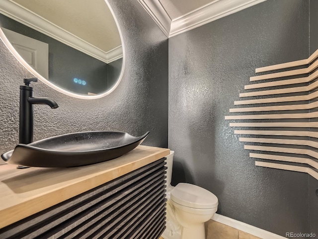 half bath with tile patterned flooring, crown molding, toilet, a textured wall, and vanity