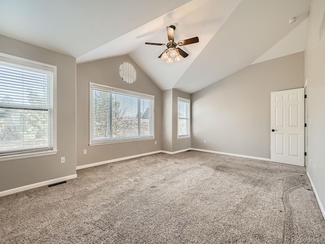 carpeted empty room with a ceiling fan, vaulted ceiling, baseboards, and visible vents