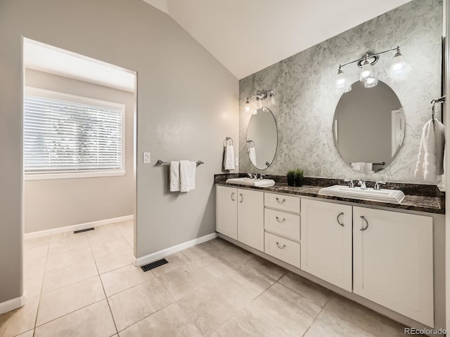 full bathroom with tile patterned flooring, baseboards, lofted ceiling, double vanity, and a sink