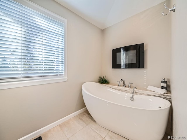 full bath featuring a freestanding tub, baseboards, and tile patterned flooring