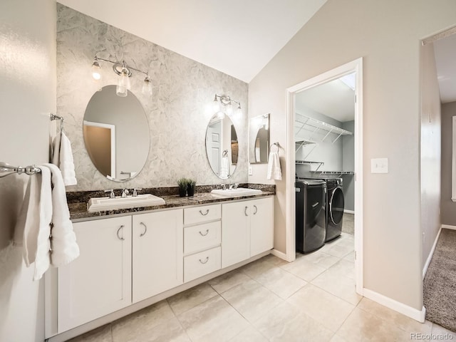 bathroom with a sink, double vanity, vaulted ceiling, and washer and clothes dryer