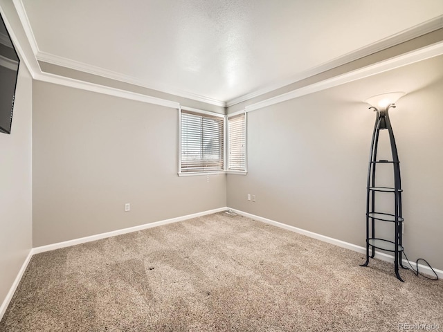 carpeted spare room featuring crown molding and baseboards