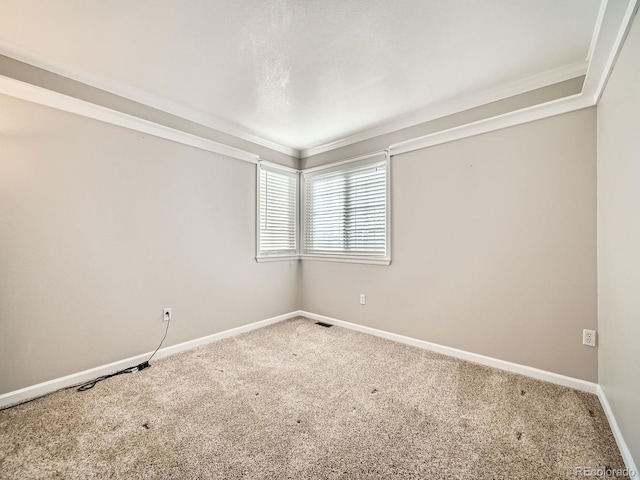 carpeted empty room with visible vents, baseboards, and ornamental molding