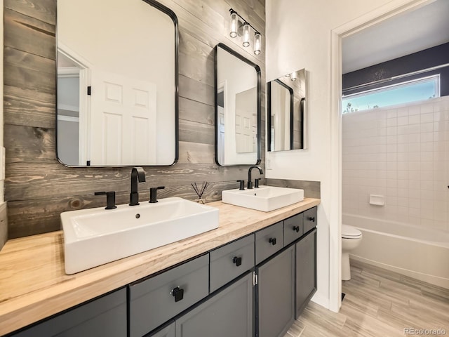 full bath featuring a sink, decorative backsplash, toilet, and double vanity