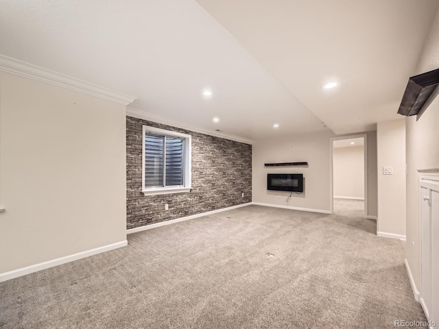 unfurnished living room featuring baseboards, brick wall, carpet floors, a fireplace, and ornamental molding