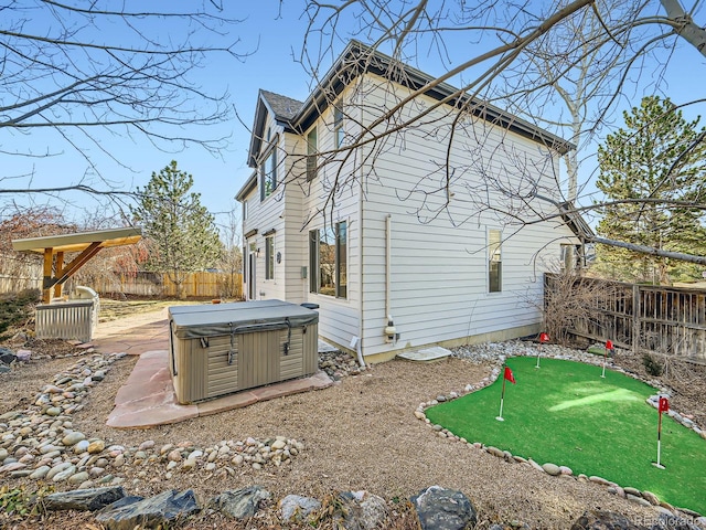 back of house featuring a fenced backyard and a hot tub