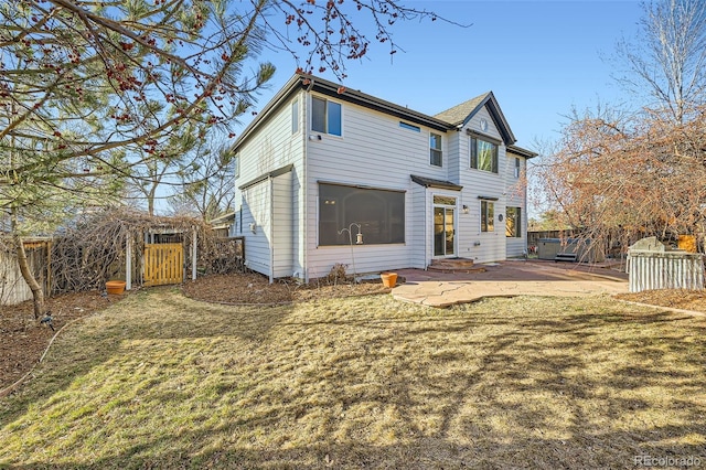 back of house featuring a lawn, a gate, entry steps, fence, and a patio area