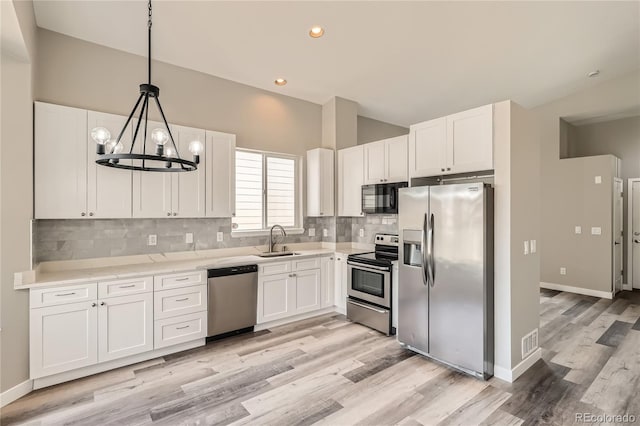 10626 Cherrybrook Cir, Highlands Ranch, CO 80126 - kitchen with appliances with stainless steel finishes, light wood-type flooring, white cabinets, backsplash, and decorative light fixtures