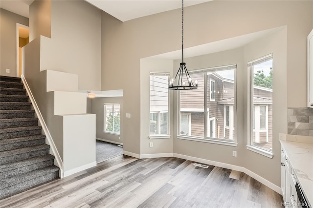 10626 Cherrybrook Cir, Highlands Ranch, CO 80126 - unfurnished dining area with a chandelier, wood finished floors, healthy amount of natural light, and a high ceiling