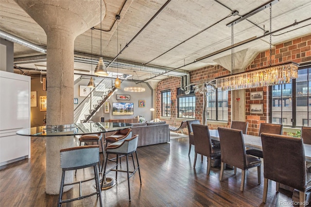 1863 Wazee St Unit 6B, Denver, CO 80202 - dining room featuring dark wood-style floors, brick wall, stairs, a chandelier, and healthy amount of natural light
