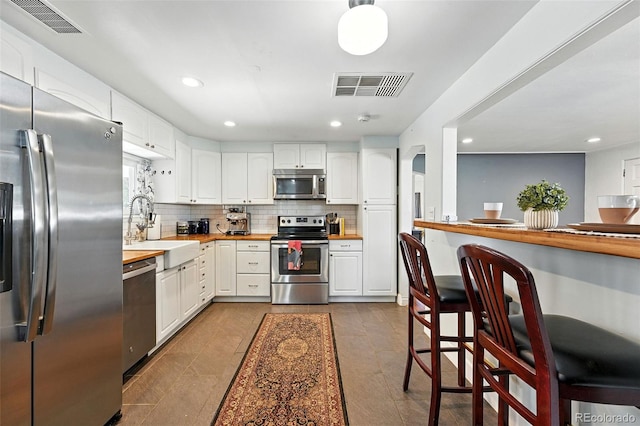 4315 S Elati St, Englewood, CO 80110 - kitchen featuring appliances with stainless steel finishes, recessed lighting, backsplash, white cabinetry, and butcher block countertops