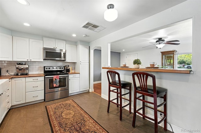 4315 S Elati St, Englewood, CO 80110 - kitchen featuring stainless steel appliances, tasteful backsplash, white cabinetry, a kitchen breakfast bar, and recessed lighting