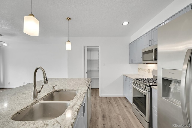 641 E 104th Pl, Northglenn, CO 80233 - kitchen featuring stainless steel appliances, a sink, light wood-style floors, pendant lighting, and a textured ceiling