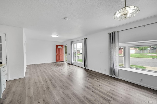 641 E 104th Pl, Northglenn, CO 80233 - unfurnished living room with light wood-style flooring, a textured ceiling, and baseboards