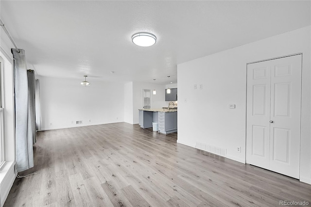 641 E 104th Pl, Northglenn, CO 80233 - unfurnished living room featuring light wood finished floors, a sink, healthy amount of natural light, and baseboards