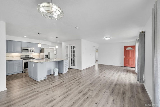 641 E 104th Pl, Northglenn, CO 80233 - kitchen with appliances with stainless steel finishes, light wood finished floors, open floor plan, baseboards, and an island with sink