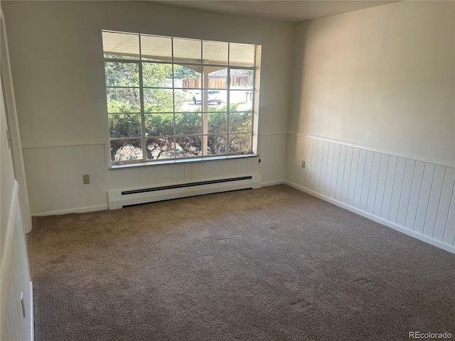 spare room with wainscoting, baseboard heating, and carpet flooring