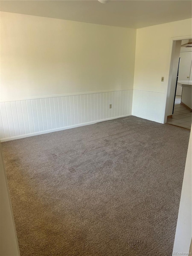 spare room featuring a wainscoted wall and carpet