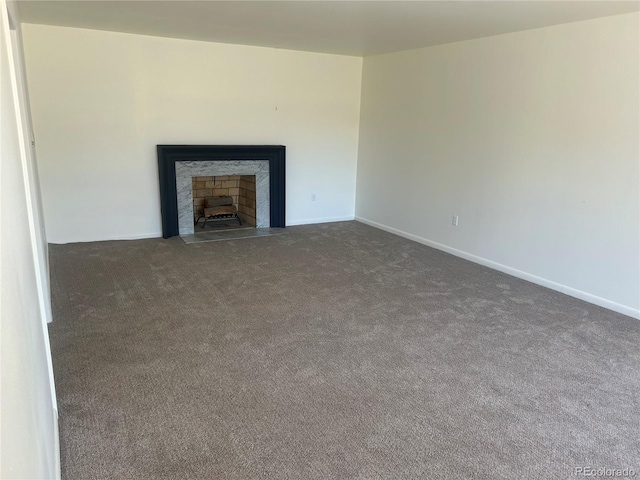 unfurnished living room with a fireplace with flush hearth, baseboards, and carpet floors