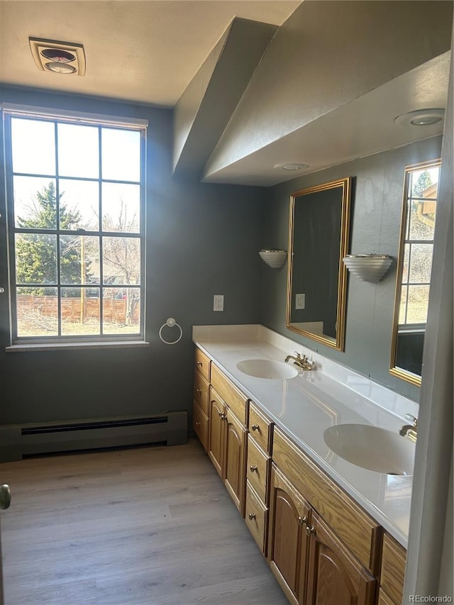 bathroom with a baseboard heating unit, a healthy amount of sunlight, visible vents, and a sink