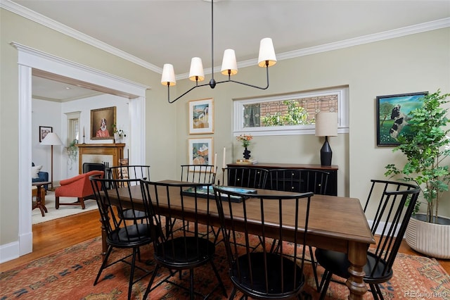 747 N Downing St, Denver, CO 80218 - dining space with wood finished floors, ornamental molding, a chandelier, and a fireplace