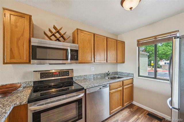 7474 E Arkansas Ave Unit 13-02, Denver, CO 80231 - kitchen with appliances with stainless steel finishes, a sink, wood finished floors, baseboards, and brown cabinetry