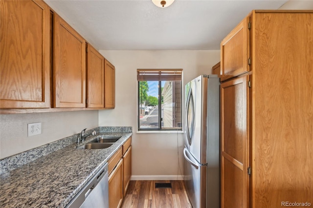 7474 E Arkansas Ave Unit 13-02, Denver, CO 80231 - kitchen featuring appliances with stainless steel finishes, a sink, baseboards, wood finished floors, and brown cabinetry