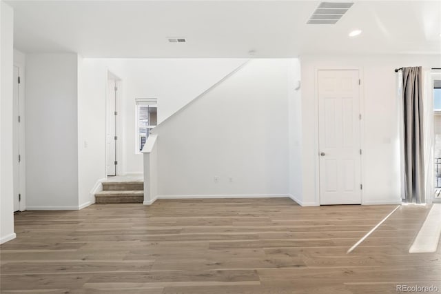 unfurnished living room with visible vents, stairs, and light wood-style floors