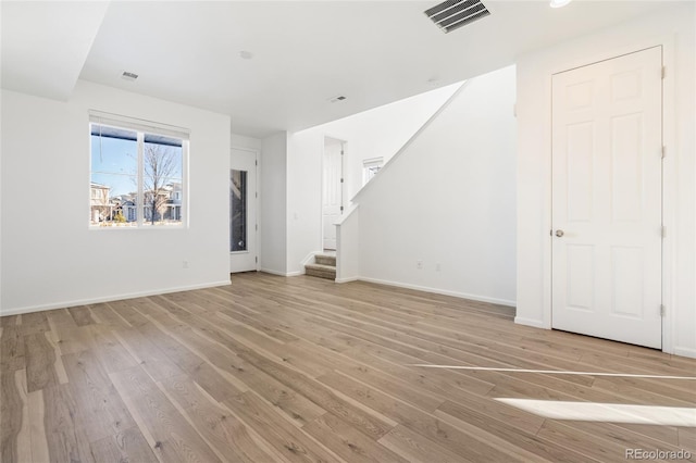 unfurnished living room featuring stairway, baseboards, visible vents, and light wood finished floors