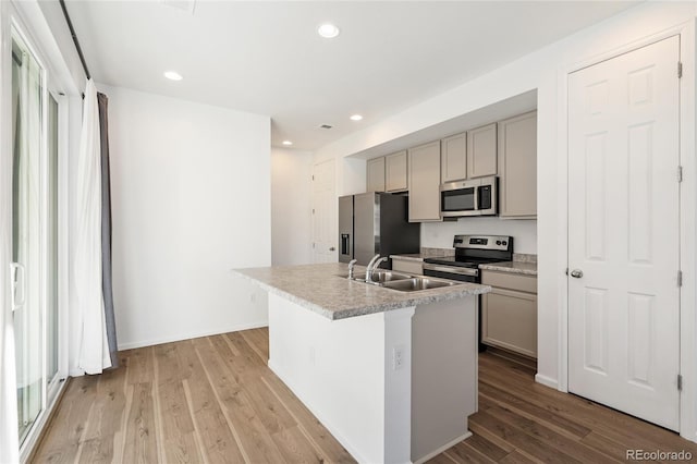 kitchen with a sink, light wood-type flooring, appliances with stainless steel finishes, and gray cabinetry