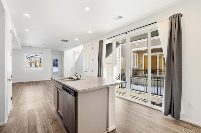 kitchen featuring visible vents, dishwasher, light wood-style floors, and a sink