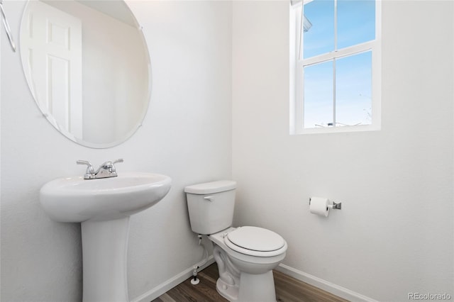 bathroom with toilet, wood finished floors, baseboards, and a sink