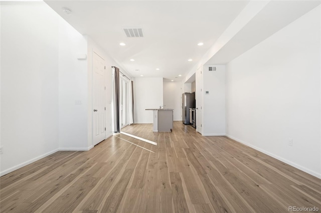 empty room with light wood-type flooring, visible vents, baseboards, and recessed lighting