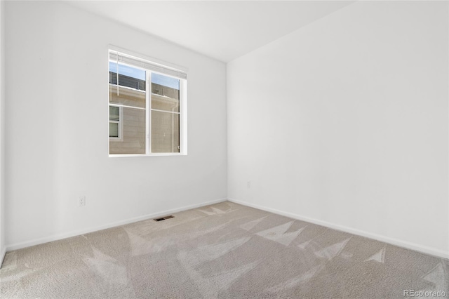 carpeted spare room with visible vents and baseboards