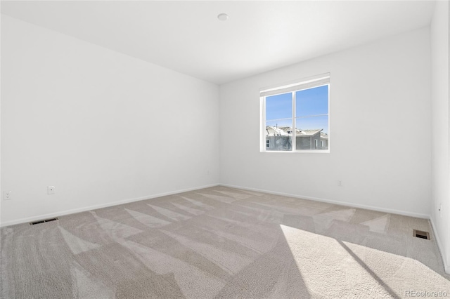 empty room with visible vents, light carpet, and baseboards