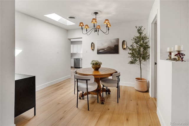 4567 Grove St, Denver, CO 80211 - dining room featuring a skylight, light wood-style flooring, a chandelier, and baseboards