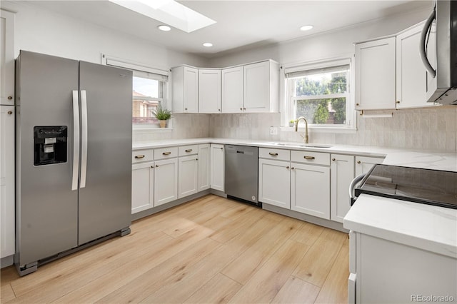 4567 Grove St, Denver, CO 80211 - kitchen featuring stainless steel appliances, a sink, a skylight, light wood finished floors, and decorative backsplash