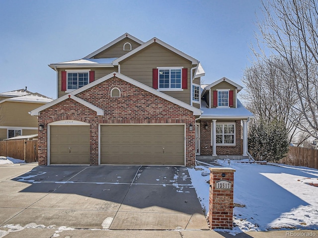 traditional-style house with a garage, driveway, brick siding, and fence