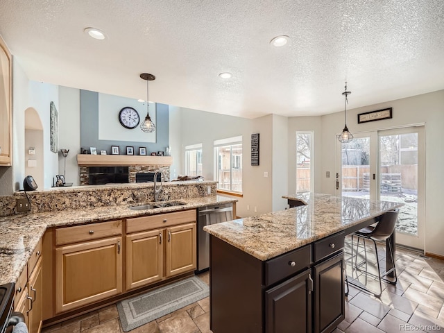 kitchen featuring dishwasher, light stone counters, a kitchen breakfast bar, decorative light fixtures, and a sink